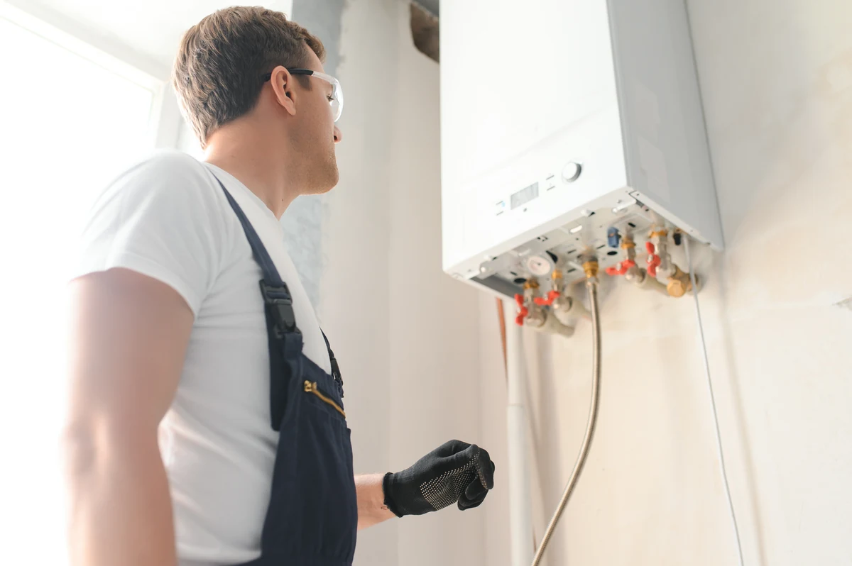 Instalator ogląda nowy wiszący podgrzewacz wody zamontowany na ścianie w domu
