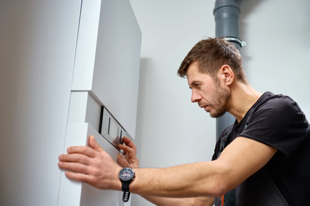 Instalator montuje na ścianie sterownik pokojowy systemu ogrzewania