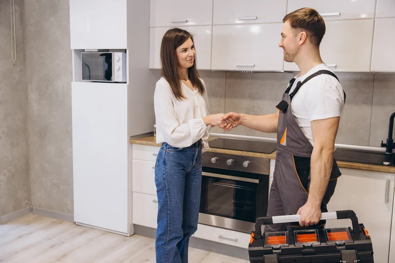 Klientka podaje rękę instalatorowi w kuchni po zakończeniu prac — odbiór zlecenia
