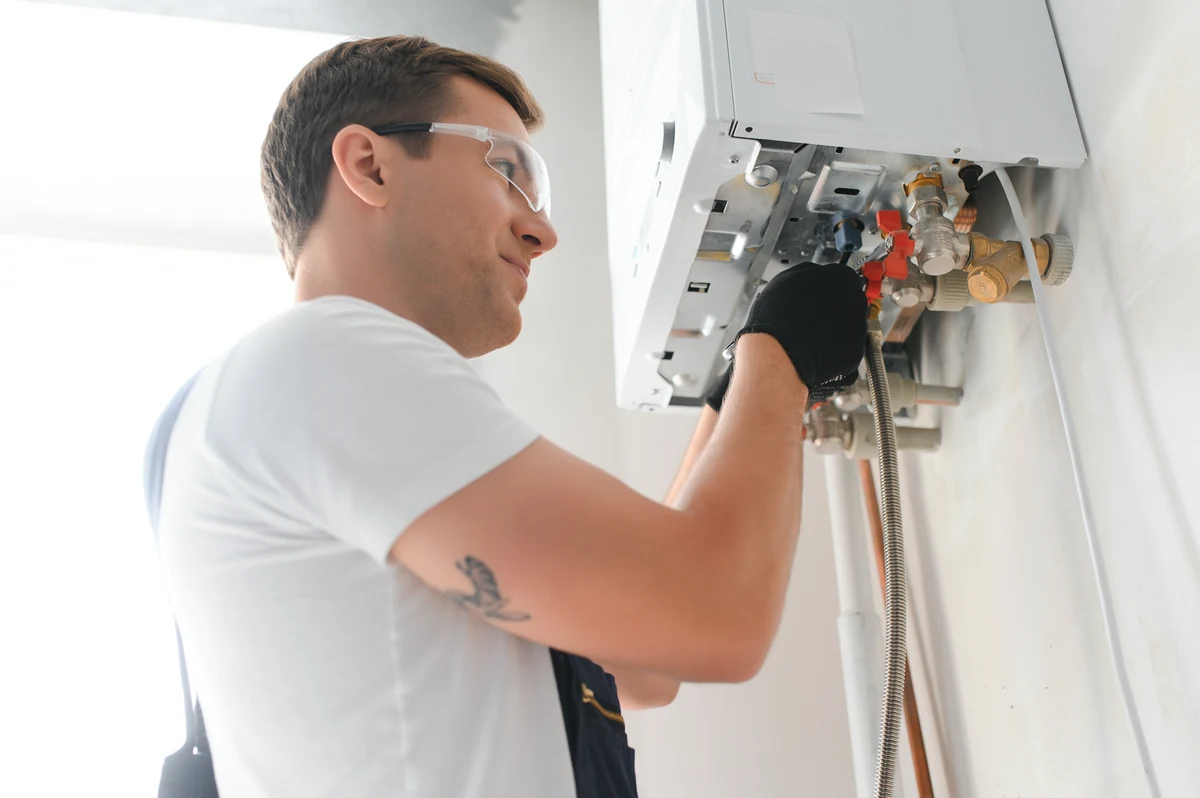 Instalator w okularach ochronnych pracuje przy otwartym kotle gazowym zawieszonym na ścianie — serwis kotłów w Bielsku-Białej